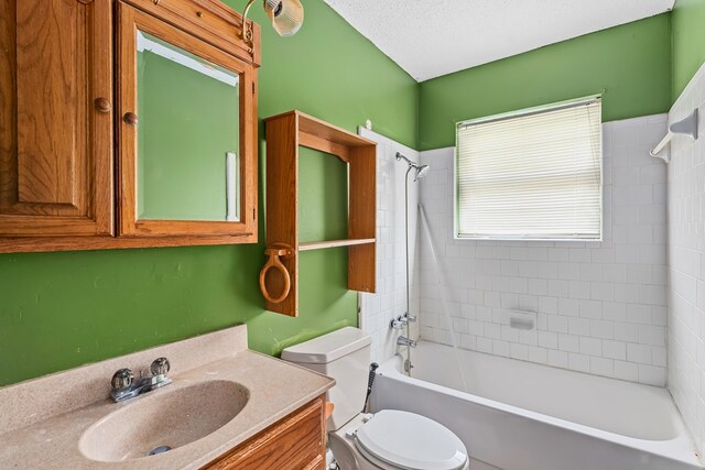 full bathroom featuring a textured ceiling, vanity, toilet, and tiled shower / bath