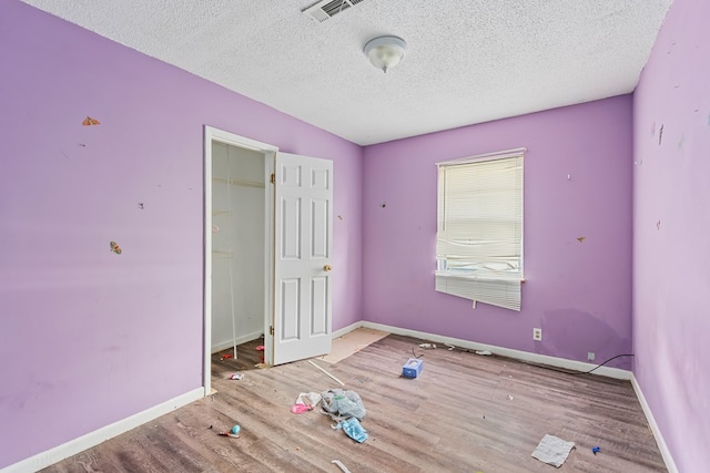 unfurnished bedroom with a textured ceiling, hardwood / wood-style flooring, and a closet