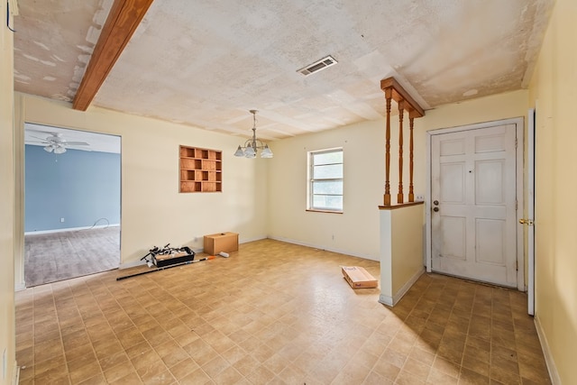 empty room with ceiling fan with notable chandelier, a textured ceiling, and beamed ceiling