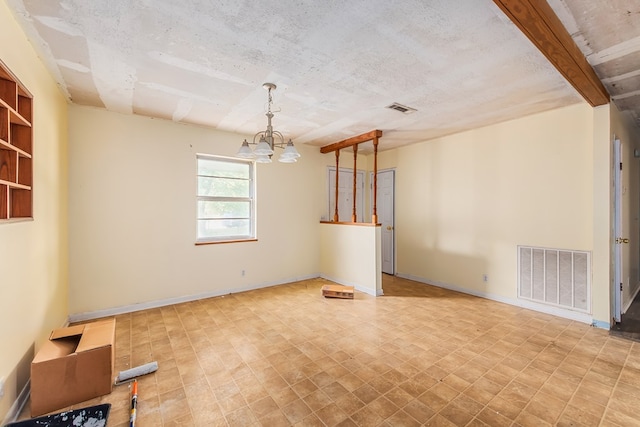 unfurnished room with a notable chandelier, beam ceiling, and a textured ceiling