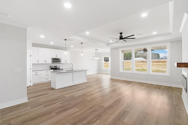 kitchen featuring appliances with stainless steel finishes, sink, white cabinets, a raised ceiling, and a center island with sink