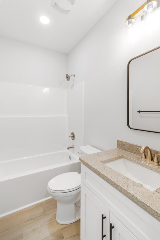 full bathroom with vanity, toilet,  shower combination, and hardwood / wood-style floors