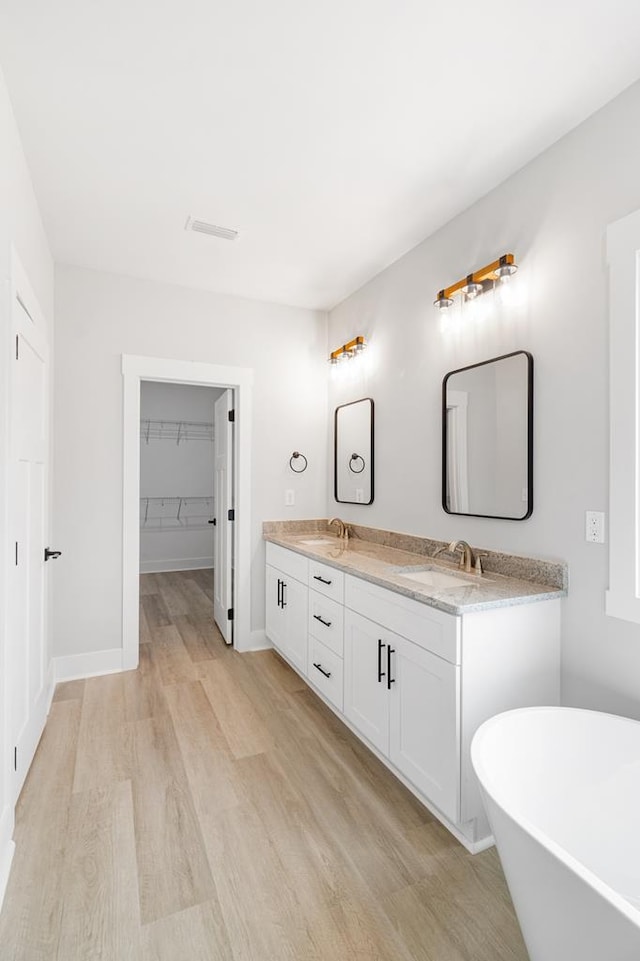 bathroom featuring hardwood / wood-style flooring, vanity, and a bath