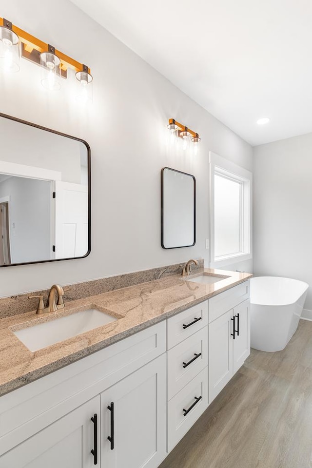 bathroom with hardwood / wood-style flooring, vanity, and a bath