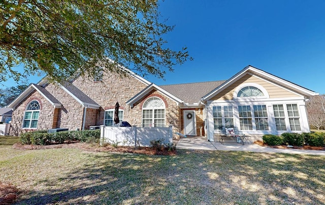 single story home featuring a patio area, stone siding, and a front yard