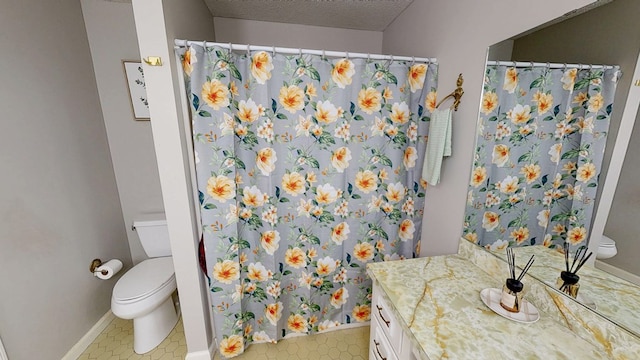 full bath featuring toilet, vanity, a textured ceiling, tile patterned flooring, and baseboards