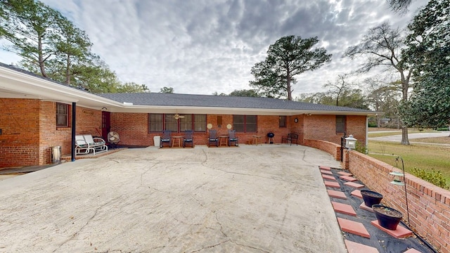 rear view of property featuring brick siding and a patio area