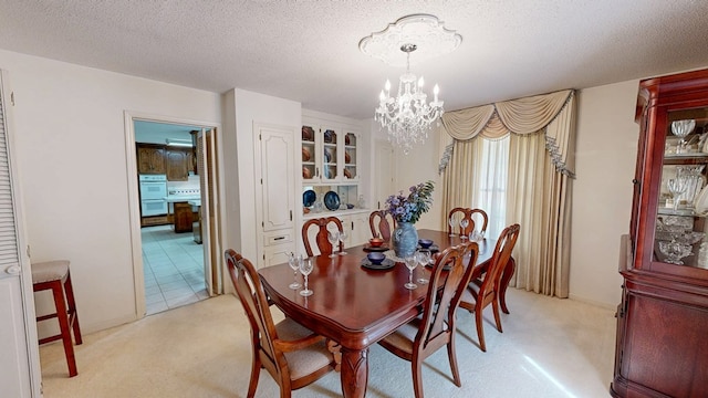 dining area featuring a chandelier, a textured ceiling, and light carpet