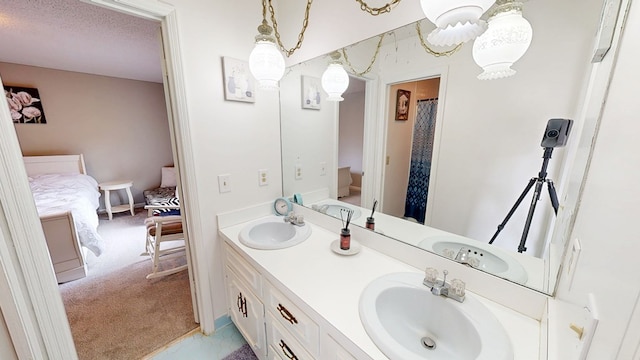 full bath with a textured ceiling, double vanity, a sink, and connected bathroom