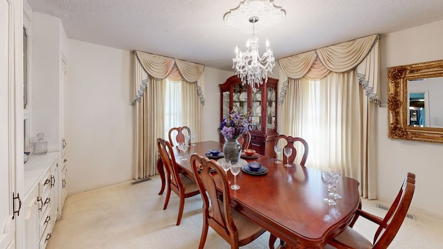 dining room with a textured ceiling, a notable chandelier, and light colored carpet