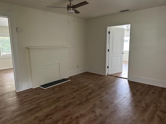 unfurnished living room with ceiling fan, dark wood-type flooring, and a brick fireplace