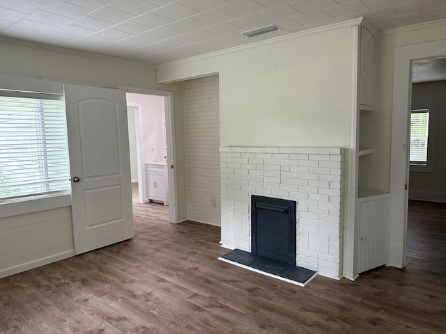 unfurnished living room featuring wood-type flooring, a fireplace, and ornamental molding