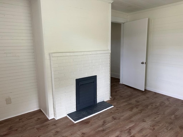 unfurnished living room featuring ornamental molding, dark wood-type flooring, and a brick fireplace