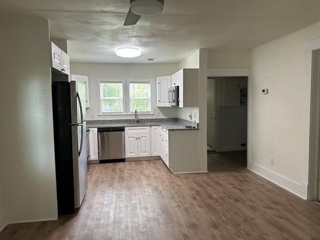 kitchen with white cabinets, hardwood / wood-style floors, stainless steel appliances, and sink