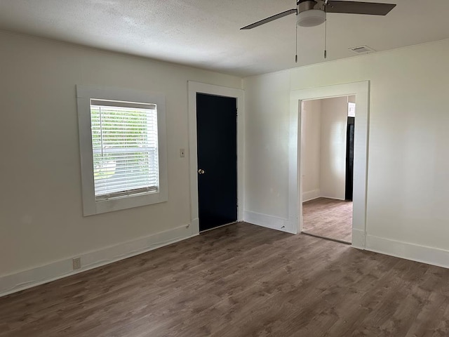 empty room featuring a textured ceiling, dark hardwood / wood-style flooring, and ceiling fan