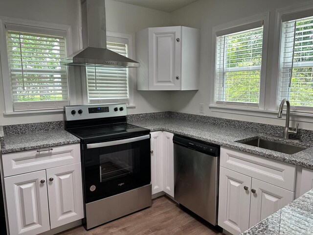 kitchen featuring white cabinetry, sink, wall chimney exhaust hood, a healthy amount of sunlight, and appliances with stainless steel finishes