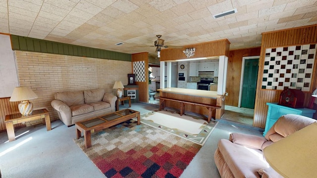 living area featuring a ceiling fan, wooden walls, brick wall, visible vents, and carpet