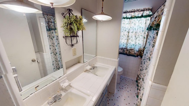 bathroom featuring tile walls, toilet, tile patterned flooring, and a sink