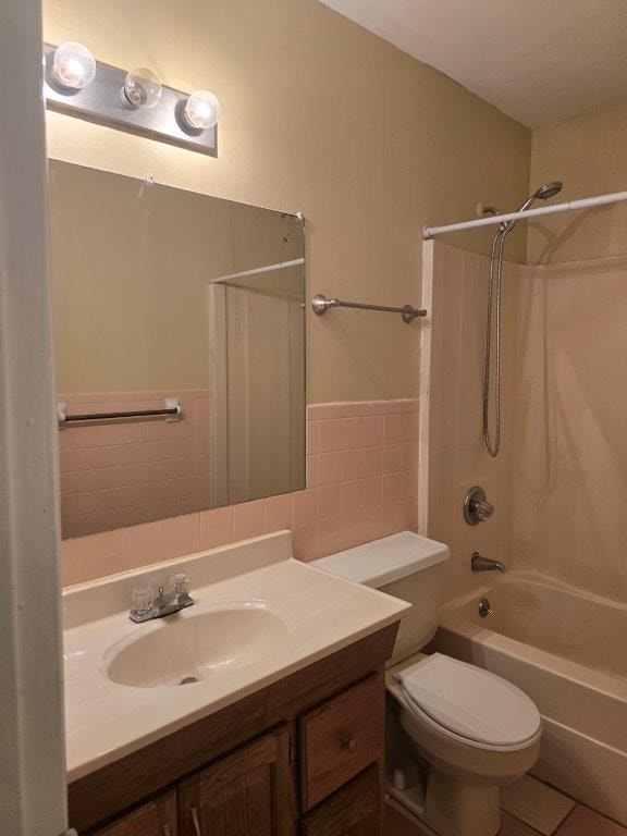 826 Old Newton Rd, Daleville, AL 36322 - bathroom with tile walls, vanity, toilet, bathtub / shower combination, and a wainscoted wall