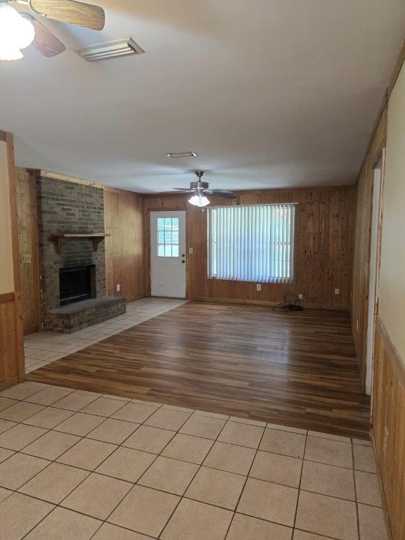 826 Old Newton Rd, Daleville, AL 36322 - unfurnished living room featuring a ceiling fan, wood walls, light wood-type flooring, and a brick fireplace