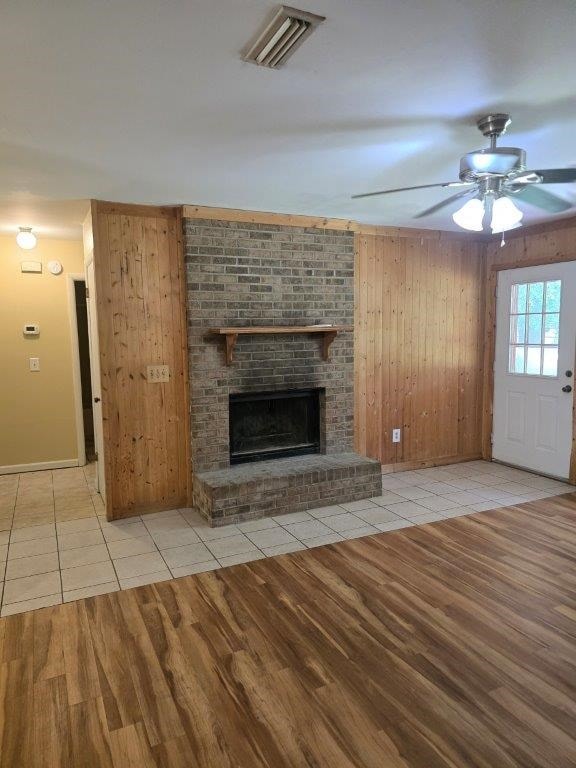 826 Old Newton Rd, Daleville, AL 36322 - unfurnished living room with tile patterned floors, ceiling fan, wooden walls, a brick fireplace, and baseboards