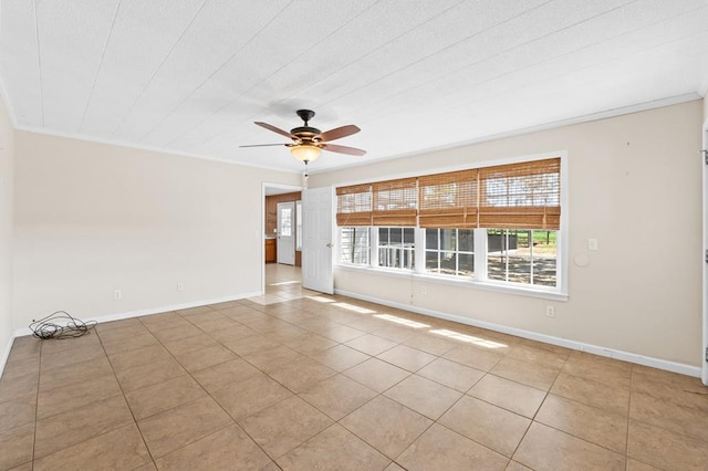 tiled empty room with ornamental molding, baseboards, and a ceiling fan