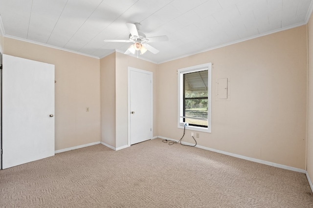 spare room featuring light carpet, baseboards, ornamental molding, and a ceiling fan