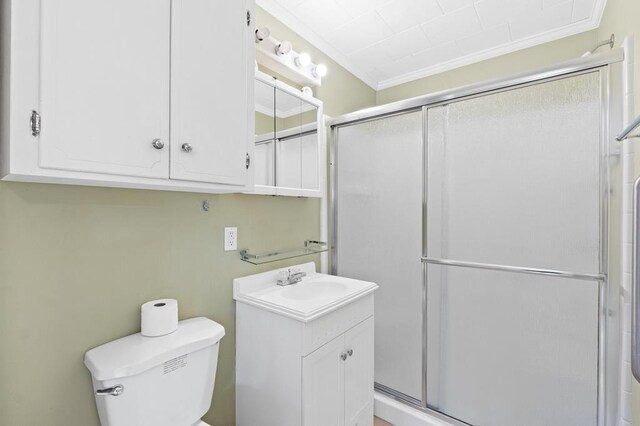 bathroom with toilet, vanity, an enclosed shower, and ornamental molding