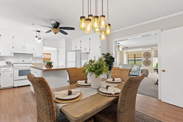 dining space with ceiling fan, ornamental molding, and light wood-style floors