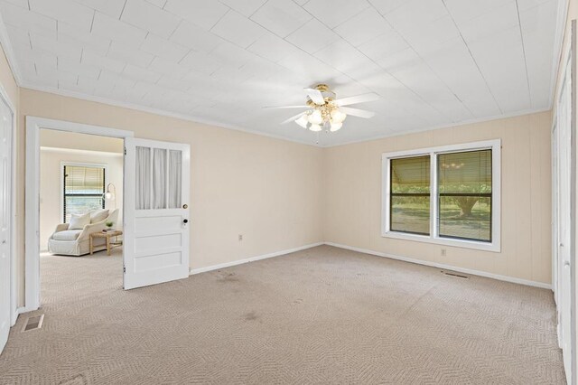 carpeted spare room featuring ceiling fan and crown molding