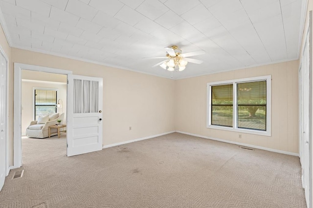 unfurnished room featuring baseboards, carpet, visible vents, and crown molding