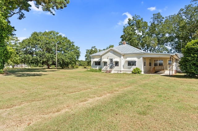 rear view of house featuring metal roof and a lawn