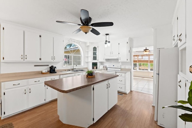 kitchen featuring white appliances, a kitchen island, white cabinets, and light wood finished floors