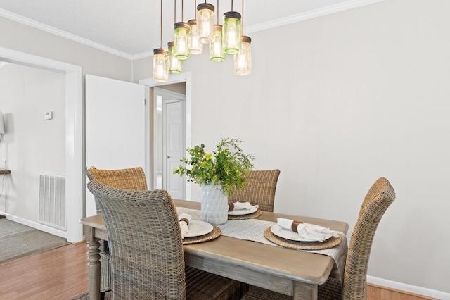 dining room with ornamental molding, visible vents, and wood finished floors