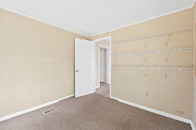 unfurnished bedroom featuring carpet, visible vents, crown molding, and baseboards