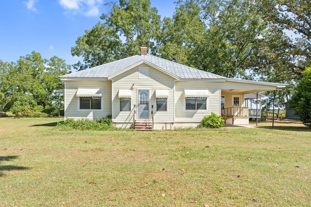 view of front of home with a chimney, entry steps, metal roof, a carport, and a front lawn