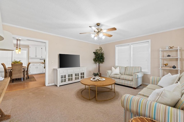 living area with ceiling fan, baseboards, light colored carpet, and crown molding