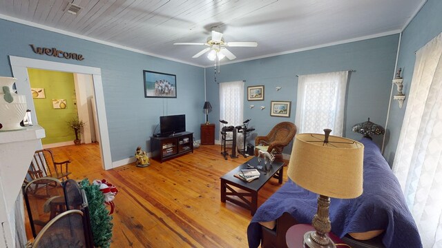 living area with visible vents, crown molding, light wood-style flooring, and ceiling fan