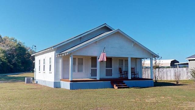 view of front of home with a porch, a front yard, fence, and central air condition unit