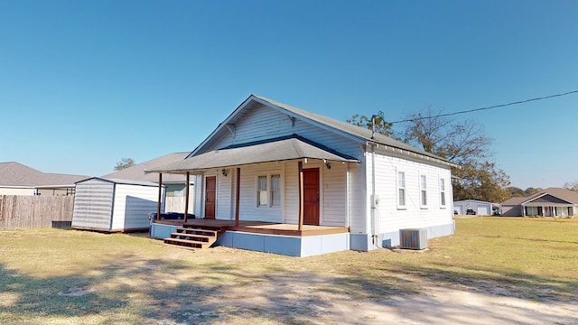 view of front of house featuring an outbuilding, a porch, a storage shed, fence, and a front lawn