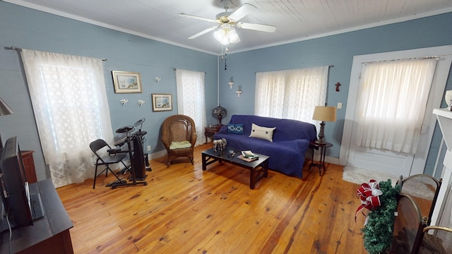 living room featuring baseboards, ceiling fan, ornamental molding, and hardwood / wood-style floors