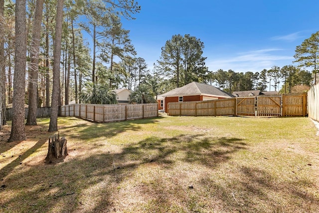 view of yard with a fenced backyard and a gate