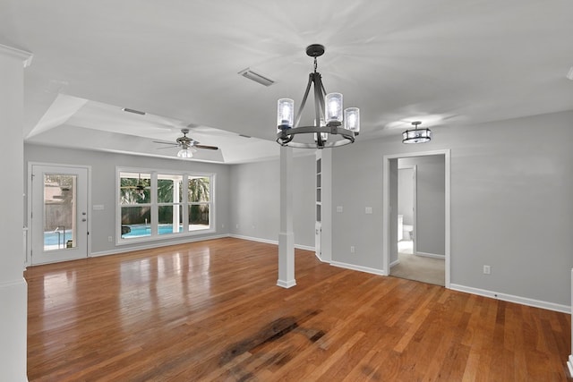 unfurnished living room with visible vents, baseboards, a tray ceiling, and wood finished floors