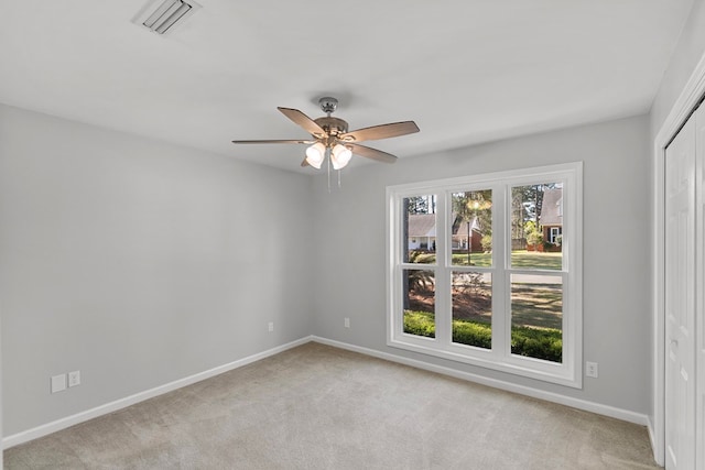 spare room featuring visible vents, baseboards, light colored carpet, and ceiling fan