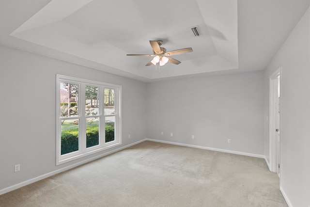 unfurnished room featuring visible vents, baseboards, carpet floors, a raised ceiling, and a ceiling fan