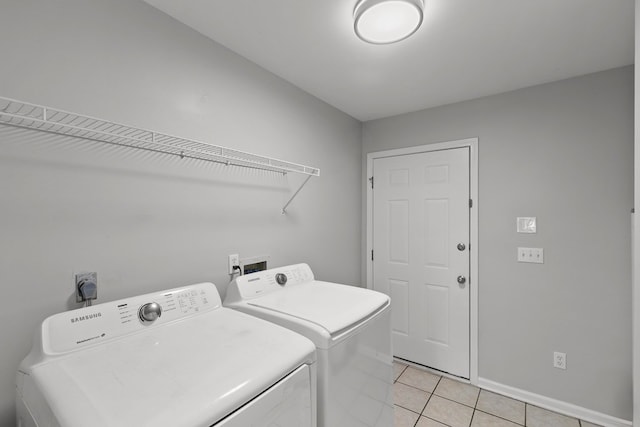 washroom featuring light tile patterned floors, laundry area, washer and dryer, and baseboards