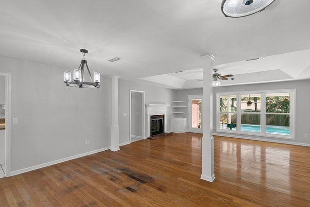 unfurnished living room with built in features, baseboards, wood finished floors, and a glass covered fireplace