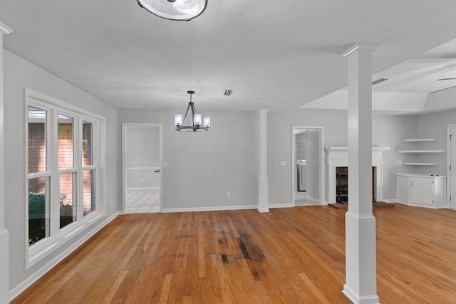 unfurnished dining area featuring decorative columns, a fireplace, and light wood-type flooring