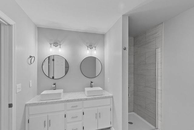 bathroom with double vanity, a shower stall, and a sink