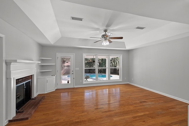 unfurnished living room featuring visible vents, a raised ceiling, and wood finished floors